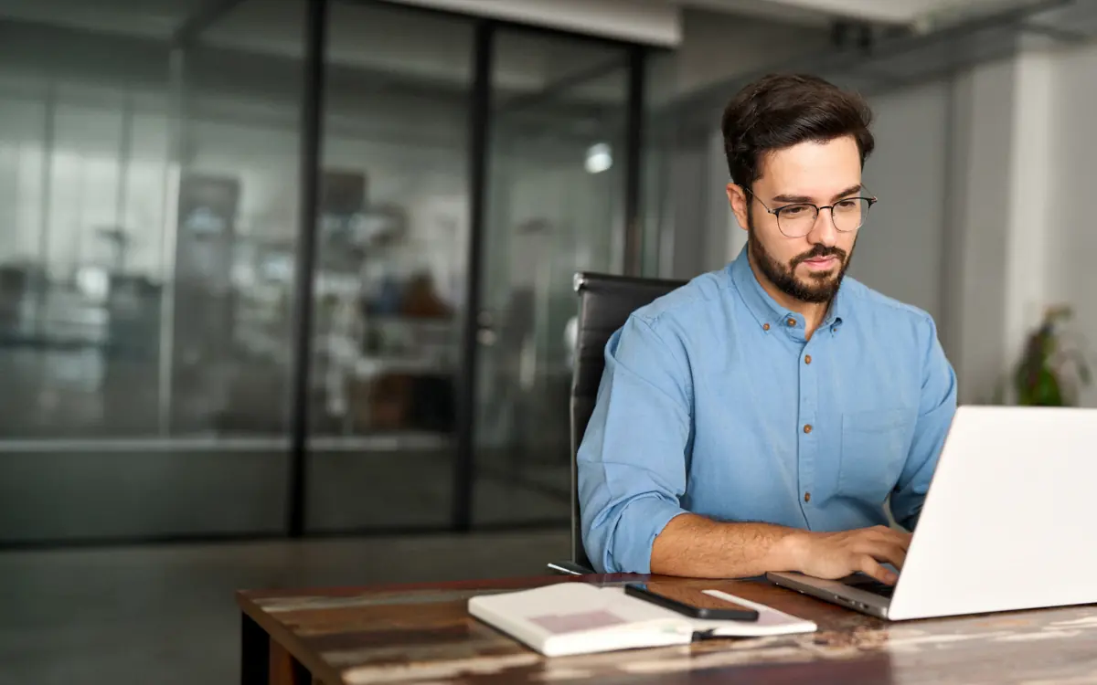 A man in a blue shirt works on his notebook in the office