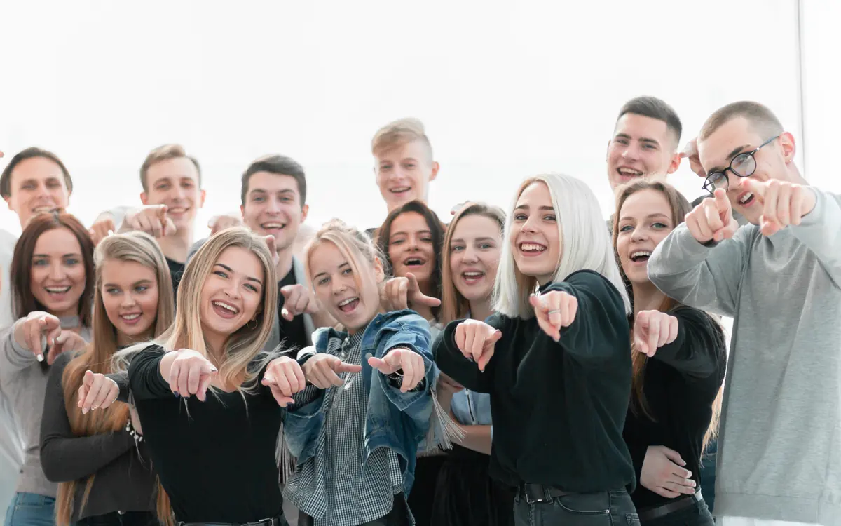 A group of young people laughing and pointing at the camera